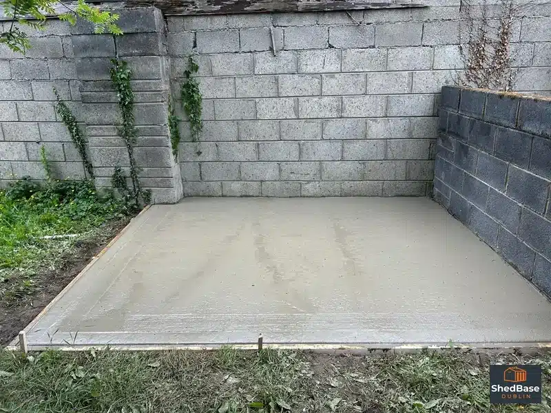 Plain grey paving slabs alongside a finished concrete shed base in a Clondalkin back garden