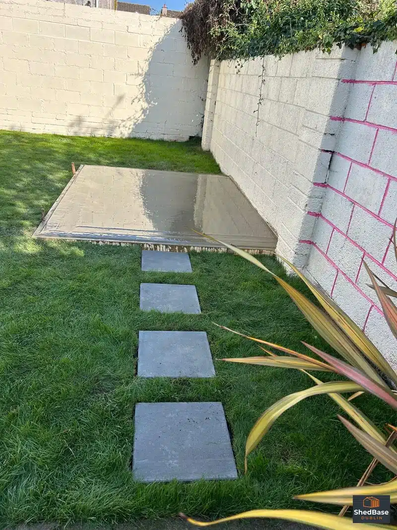 Stepping stones across a lawn leading to a newly poured concrete shed base